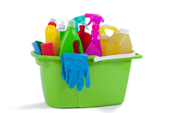 Various household cleaning supplies including detergents, gloves, sponges, and spray bottles in a green bucket. Ideal for illustrating home cleaning, sanitation, and hygiene concepts. Useful for articles, advertisements, and guides related to cleaning products and household chores.