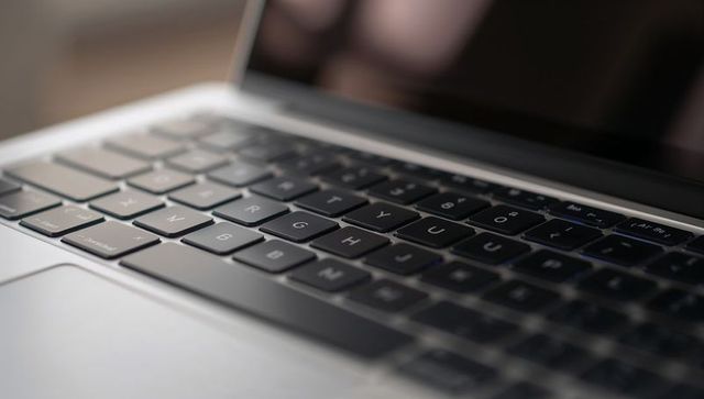 Close-up laptop keyboard resting on aluminum palm rest with sleek trackpad and soft bokeh