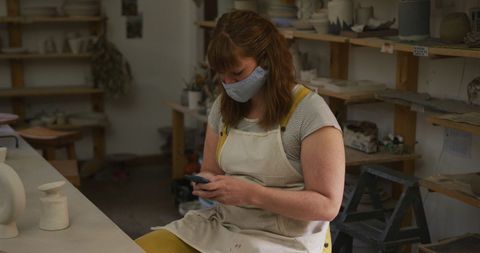 Caucasian Female Potter Using Smartphone at Pottery Studio