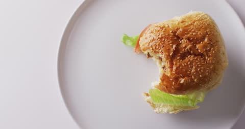 Partially Eaten Cheeseburger on White Plate with Copy Space