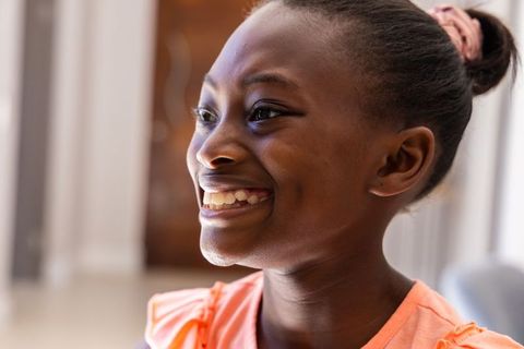 Joyful teenage girl smiling in warm natural light in coral ruffled top and pink scrunchie