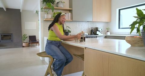 African american woman brewing french press coffee at modern open-plan kitchen island