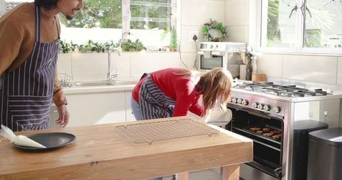 Couple baking cookies together in sunlit rustic kitchen with island and stainless stove