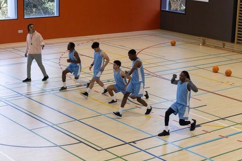 Coach guiding diverse team in basketball training session