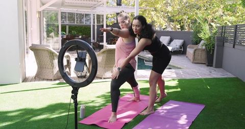 Women practicing yoga on sunny deck with instructor guidance