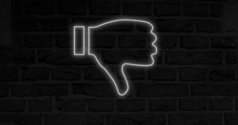 Neon thumbs down icon on dark brick wall