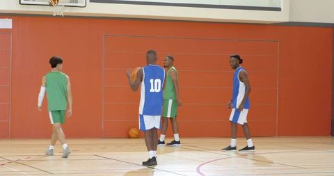 Indoor basketball players practicing rebounding and team play on gym court