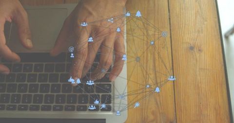 Hands typing on laptop keyboard with digital social network overlay on wooden desk overhead view