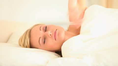 Peaceful Woman Resting Comfortably in Soft Bedding