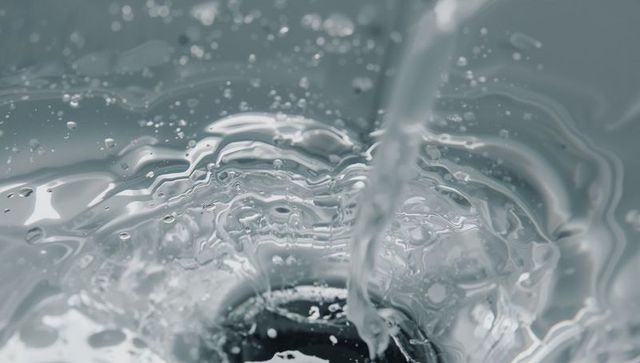 Swirling Water Vortex Pouring into Metallic Drain Creating Ringed Ripples and Droplets