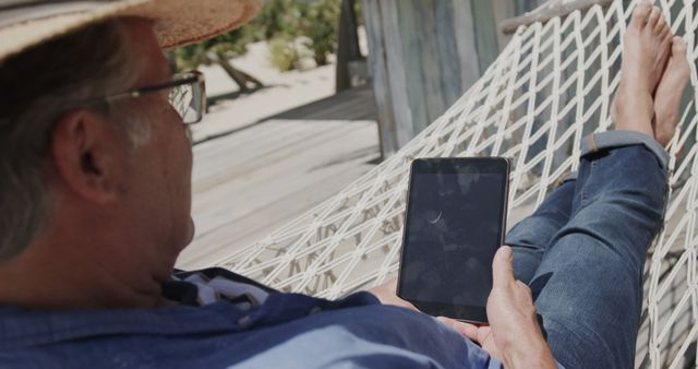 Senior Man Relaxing on a Hammock with Tablet at Beach - Download Free Stock Images Pikwizard.com