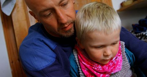 Father Assisting Young Son with Dressing Indoors
