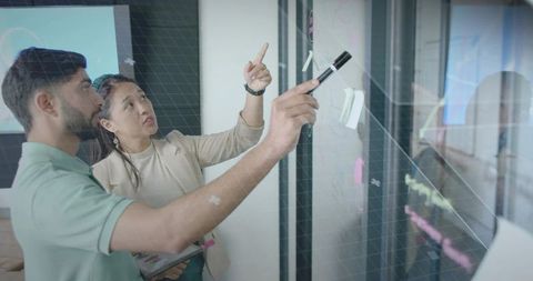 Business team collaborating with a glass board in meeting room