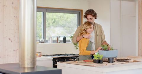 Couple transplanting herbs indoors for sustainable lifestyle