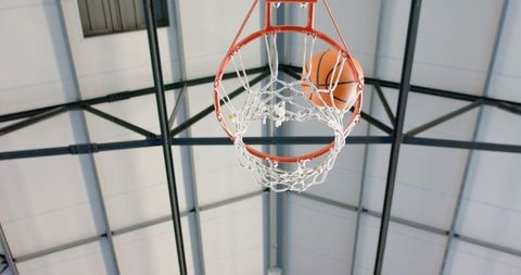 Basketball hoop with ball scoring in indoor gym