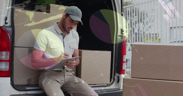 Delivery worker in casual clothing sitting on the tailgate of a van, checking shipment details on a clipboard. Large cardboard boxes are visible inside the van, indicating a busy day of deliveries. Useful for themes related to delivery services, logistics, courier companies, shipping or supply chain management.