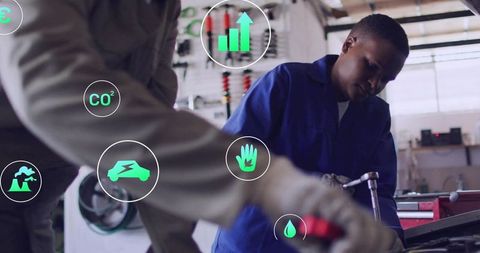 Young auto technician diagnosing engine with digital eco icons showing sustainability