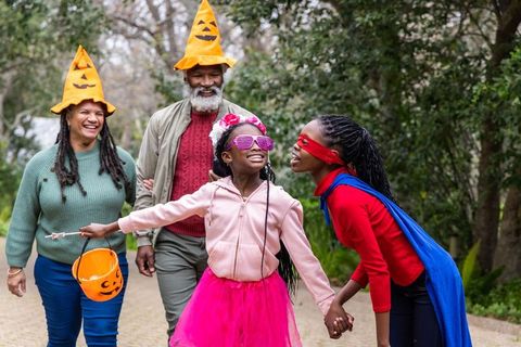 African american family walking celebrating halloween in neighborhood wearing fun costumes