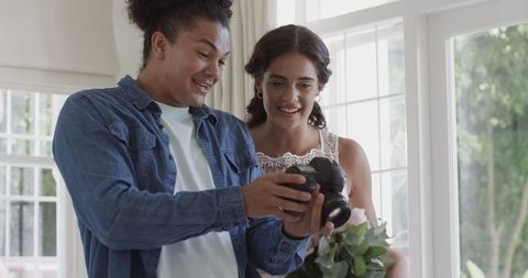 Photographer and bride reviewing wedding photos by window