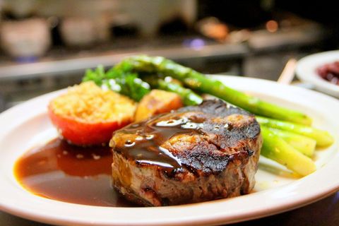 Serving Filet Mignon with Demi-Glace, Roasted Tomato and Asparagus on White Plate
