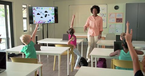 Teacher Leading Engaged Elementary Students Raising Hands in Modern Classroom