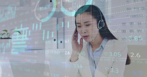 Asian Call Center Agent Analyzing Financial Data on Headset