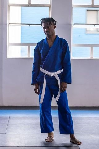 Young man training martial arts in gi and white belt in dojo