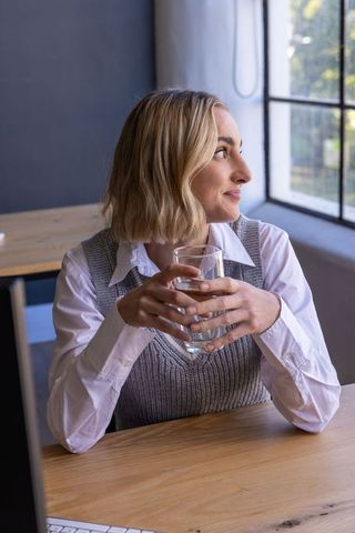 Businesswoman reflecting with water by workplace desk