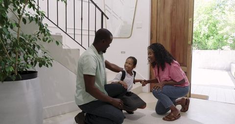 African American Parents Kneeling and Comforting Daughter in School Uniform at Home