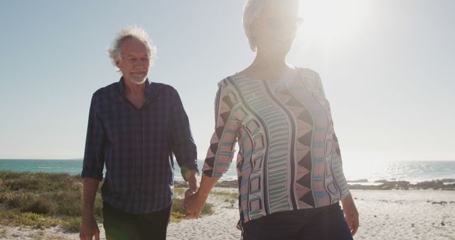 Senior couple is walking hand-in-hand on sunny beach, enjoying relaxed atmosphere. Perfect for illustrating leisure lifestyle, retirement happiness, healthy aging, and romantic relationships in later years.