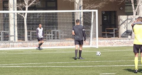 Soccer players strategizing near goal during training session