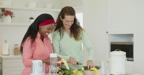 Female Friends Preparing Healthy Smoothie Together in Modern Kitchen