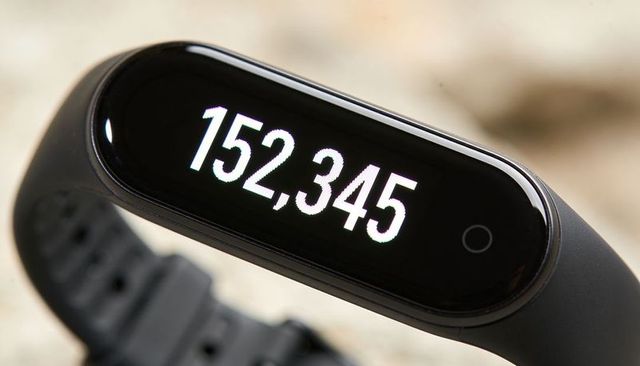Fitness tracker displaying 152,345 step count on oled screen, macro close-up of wearable band