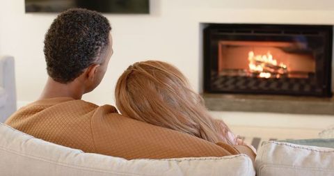 Cozy Interracial Couple Relaxing by Fireplace in Modern Living Room