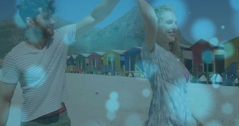 Romantic couple dancing by vibrant beach huts