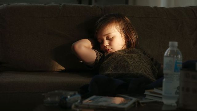 Toddler sleeping on sofa in golden sunlight, cozy home naptime, peaceful child resting