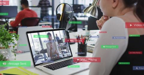 Woman Watching Laptop During Remote Video Meeting in Modern Open Office Workspace