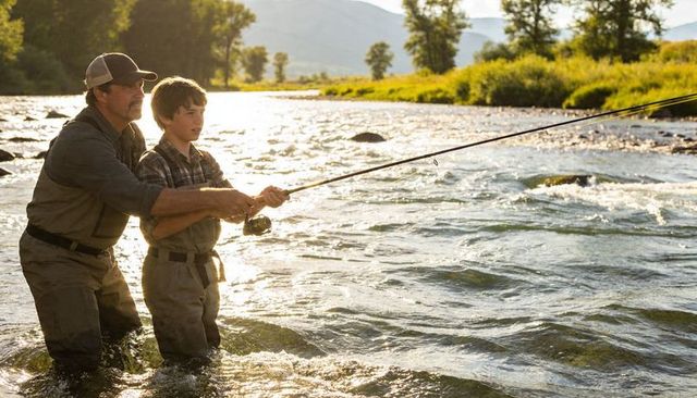 Father teaching teen fly fishing in river at sunset, bonding outdoors mentoring moment
