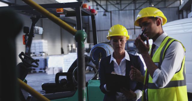 Workers in safety helmets and using walkie-talkie communicating in industrial plant. Useful for topics related to workplace safety, industrial operations, manufacturing, teamwork, and communication. Ideal for conveying professional environments, safety protocols, and efficient collaboration in trade settings.