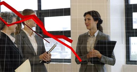 Businesswomen discussing declining performance with red downward graph overlay in office