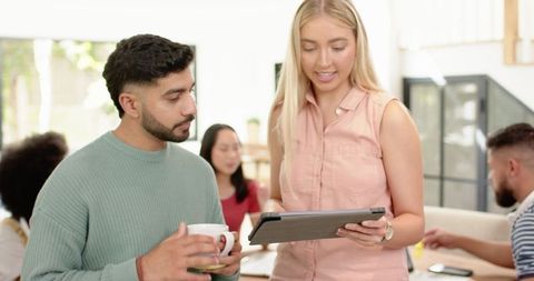 Diverse Team Collaborating in Modern Office Space with Tablet