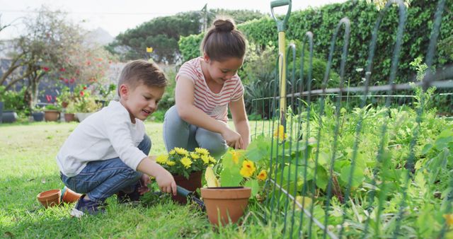 Happy caucasian siblings gardening, planting flowers together. family time, having fun together at home and garden.