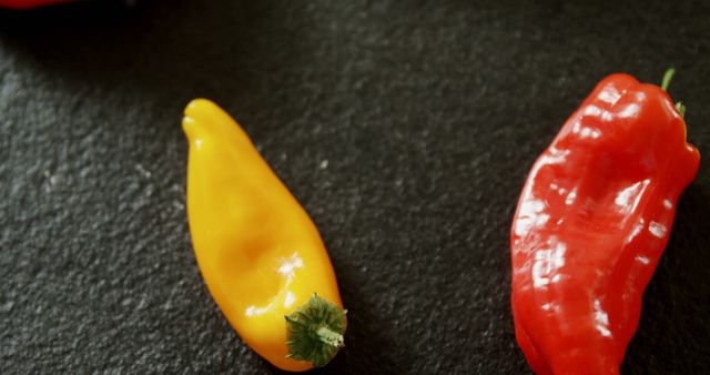 Vibrant fresh red and yellow peppers on dark slate surface. Perfect for themes on healthy eating, organic food, and culinary presentations or food blogs.