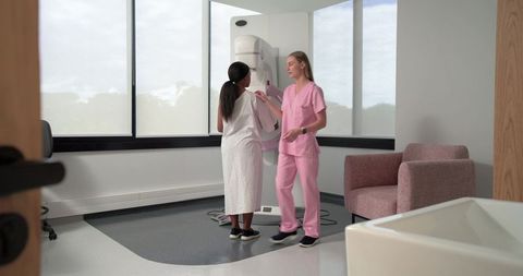 Mammography technologist assisting patient, positioning at digital breast imaging unit