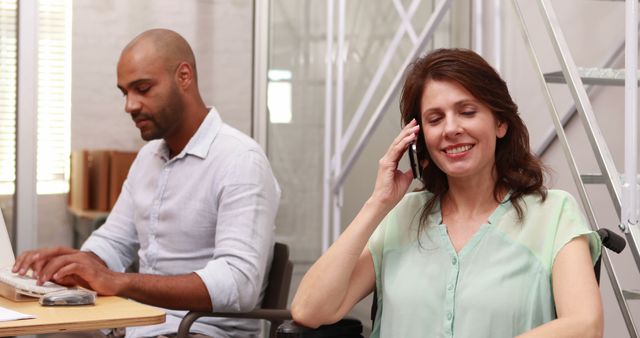 Smiling Woman Talking on Phone in Modern Office with Male Colleague Typing - Download Free Stock Images Pikwizard.com