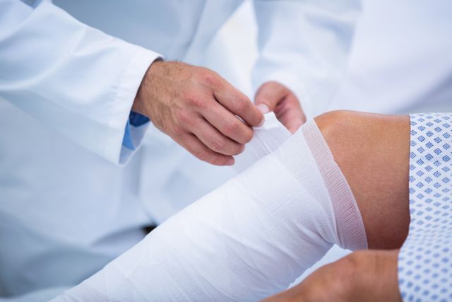 This image shows a doctor bandaging the leg of a patient in a hospital. Suitable for use in medical articles, healthcare industry materials, injury treatment guides, and hospital service promotions.