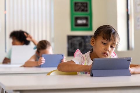 Elementary students using tablets in classroom concentrating on digital learning and STEM