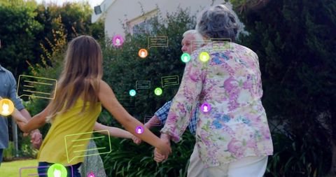 Multigenerational family holding hands on lawn while responding to colorful chat bubbles