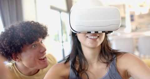 Couple enjoying virtual reality woman wearing white VR headset man reacting with surprise