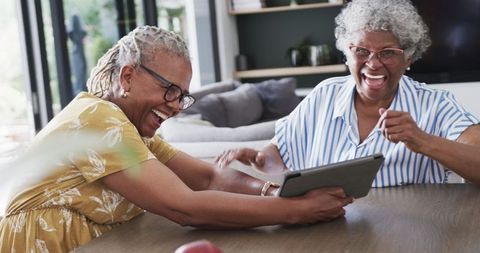 Senior African American Women Enjoying Tablet and Laughing Together